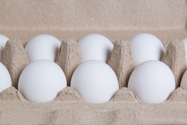 White chicken eggs in a cardboard box.