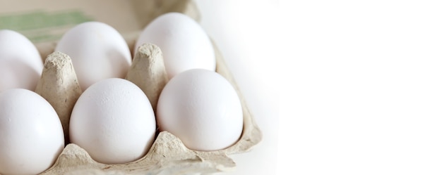 White chicken eggs in package on white isolated surface.