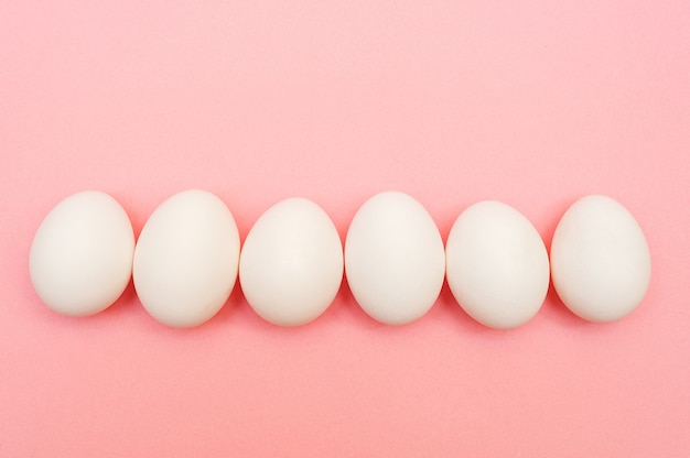 White chicken eggs on pink background