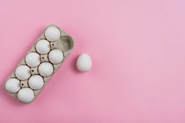 Photo white chicken eggs in rack on pink table