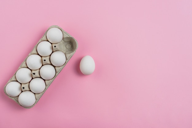 Il pollo bianco eggs in scaffale sulla tavola rosa