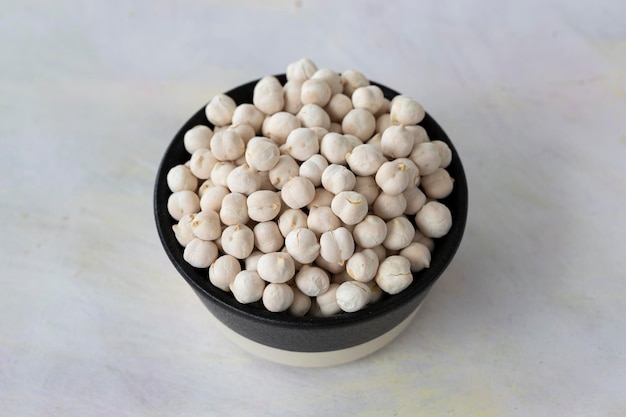 White chickpeas in bowl on white wooden background