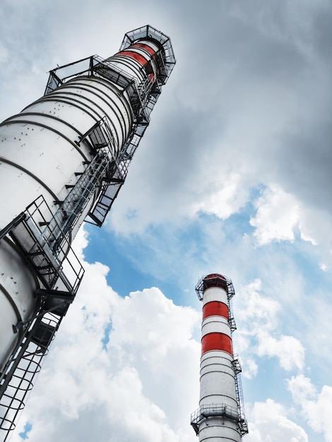 White chimneys of a power plant on a background of clouds with diagonal lines