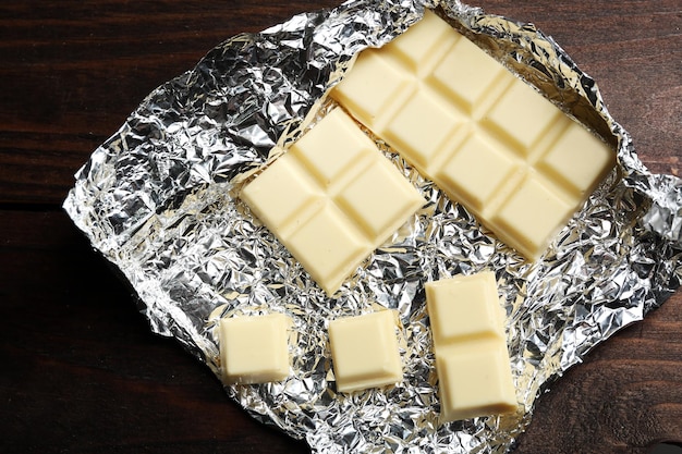 white chocolate bar in foil closeup on wooden background