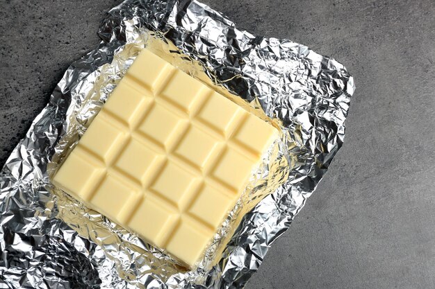 white chocolate bar in foil on gray background