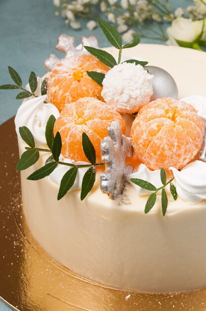 White chocolate cake decorated with tangerines on a blue background. vertical frame. close-up