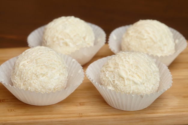 white chocolate candies with coconut topping on wooden surface