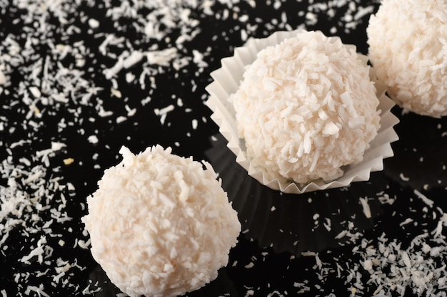 Foto caramelle al cioccolato bianco con guarnizione al cocco su sfondo nero black