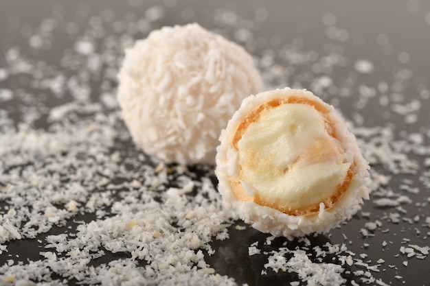 Foto caramelle al cioccolato bianco con guarnizione al cocco su sfondo nero black