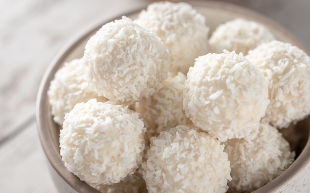 White chocolate coconut candy balls in the bowl close up, selective focus