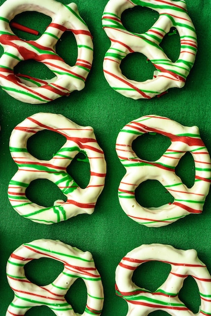 Photo white chocolate dipped pretzels decorated with red and green candy stripes flat lay