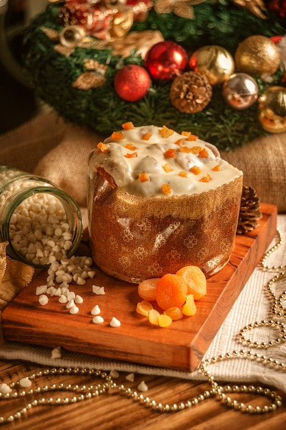 White chocolate panettone with dried apricot on wooden table with christmas ornaments