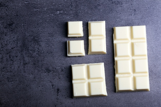 Кусочки белого шоколада на серой поверхности