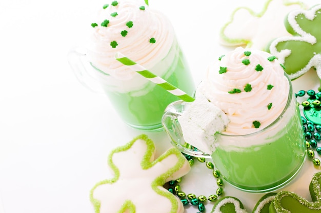 White chocolate shorrbread cookies in shape of four clover leaf with green hot chocolate.