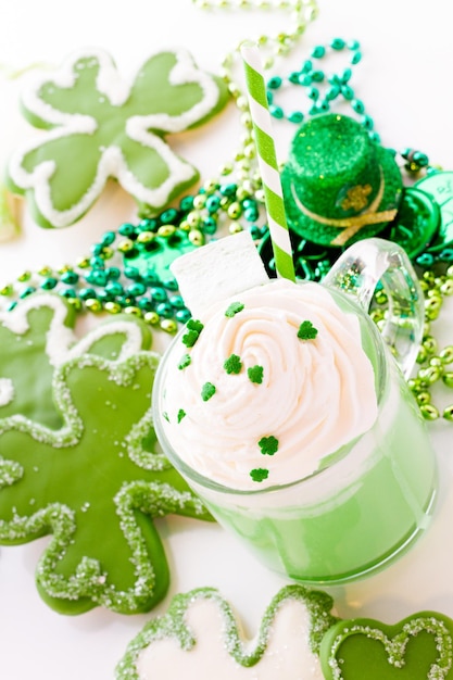 White chocolate shorrbread cookies in shape of four clover leaf with green hot chocolate.