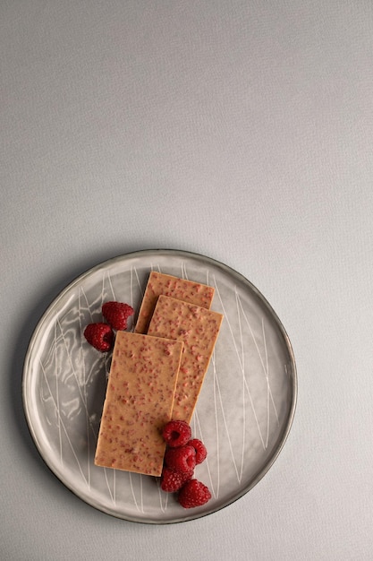 White chocolate stack and fresh and delicious raspberries on gray table Natural light selective focus