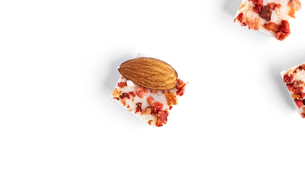 White chocolate with almonds, cranberries and strawberry slices isolated on a white surface