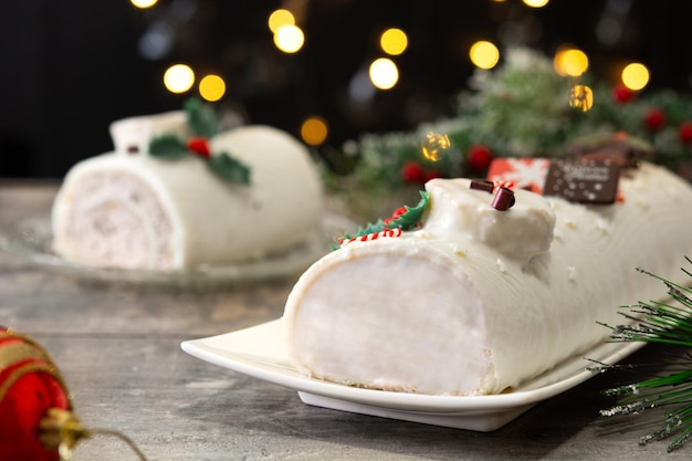 Torta di ceppo di natale al cioccolato bianco con luci di natale sul tavolo di legno