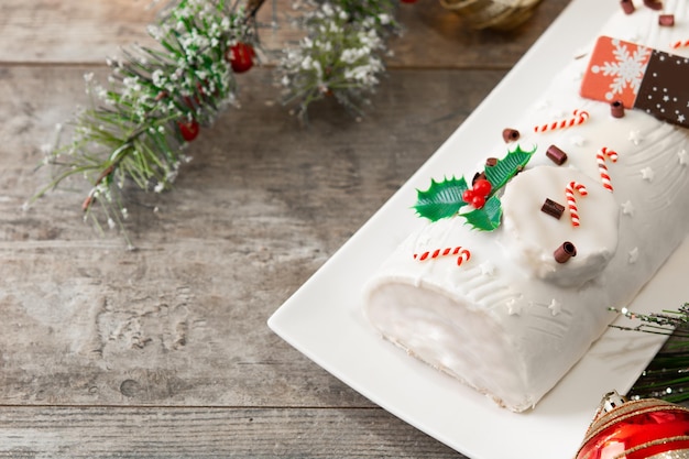 白い背景に分離されたクリスマスの飾りとホワイト チョコレート ユール ログ ケーキ