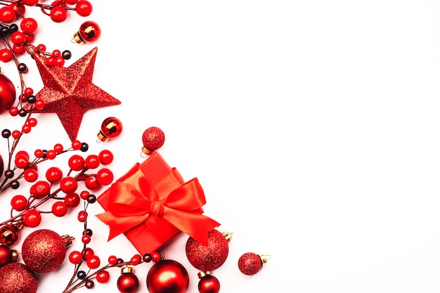 Фото Белый рождественский и новогодний фон с красными елочными шарами большая звезда и ягоды подарочные коробки вид сверху копией пространства
