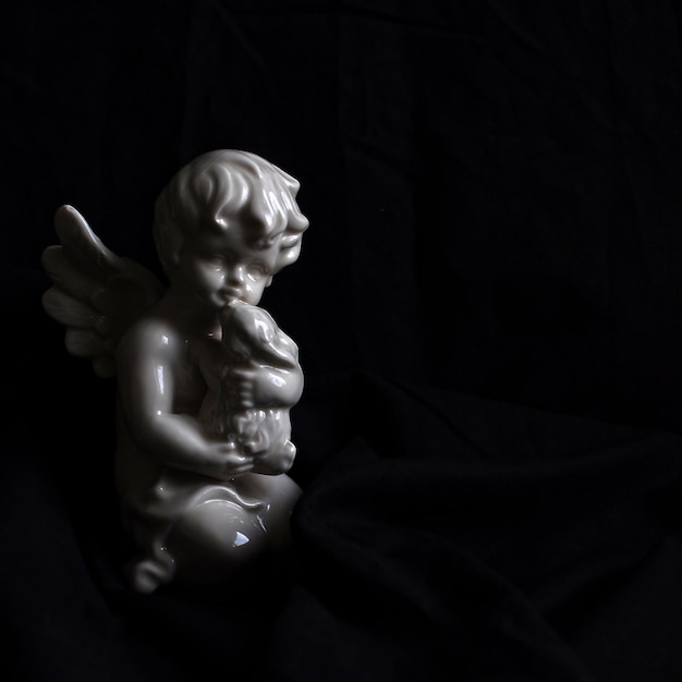 Photo white christmas angel porcelain sculpture on black background.