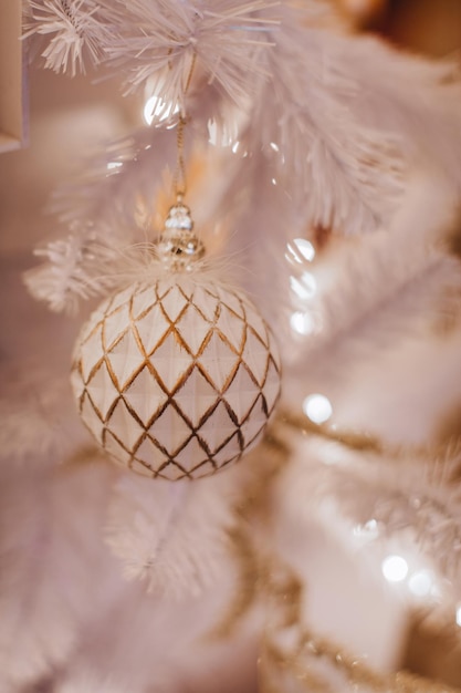 クリスマス ツリーに掛かっている黄金の飾りと白いクリスマス ボール 魔法の冬の詳細