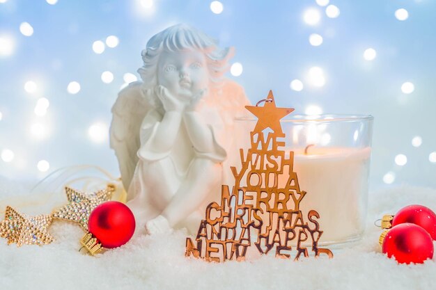 Photo white christmas cute angel with christmas tree in snow bokeh festive lights in background