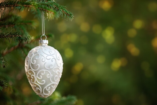 White Christmas decoration hanging on a spruce branch