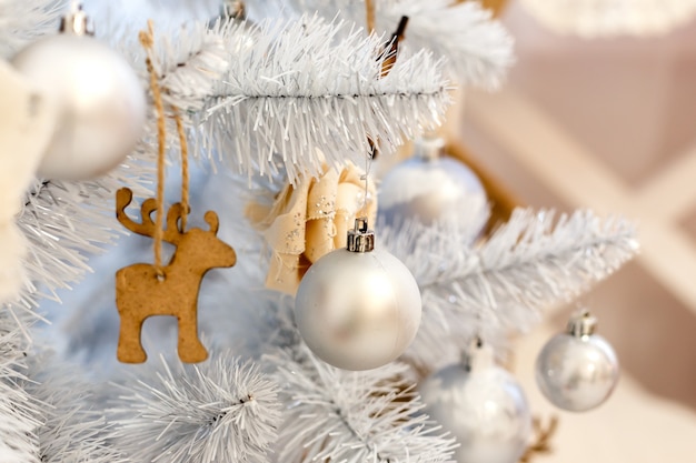 White christmas decorations balls hanging on a decorative white christmas tree. Concept New Year celebration background.