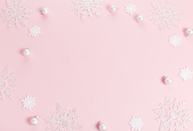 ホワイトクリスマスホリデー作曲。お祝いの創造的な白いパターン、ピンクの背景に雪片とクリスマスの装飾ホリデーボール。フラットレイ、上面図