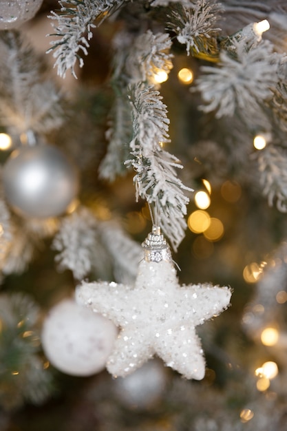 White Christmas toy hanging on a green snowy fir branch