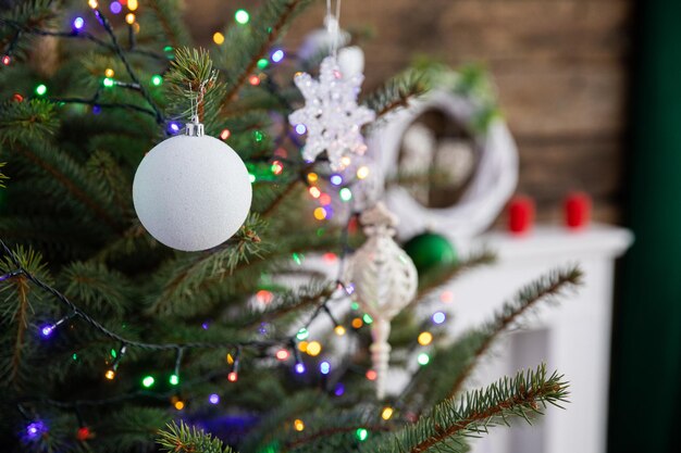 A white christmas tree bauble hangs on a branch of an entourage standing in the living room