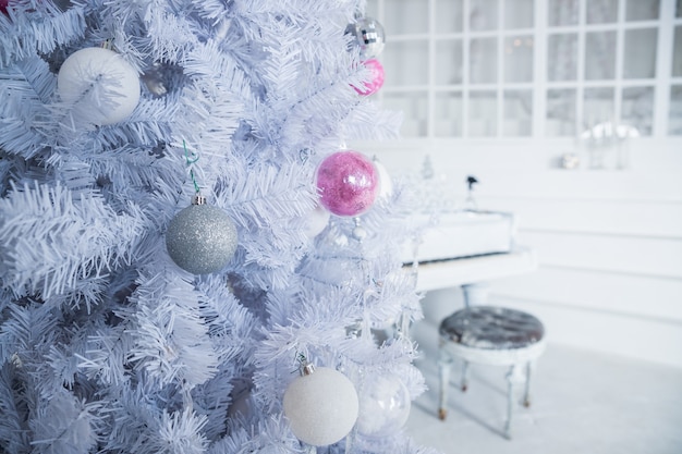 White Christmas tree decorated with silver and pink ornaments at the piano