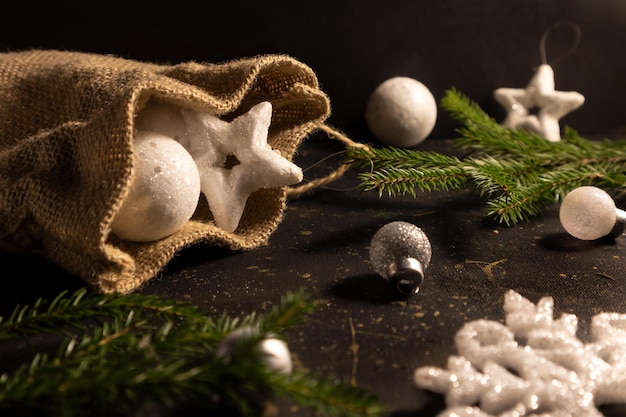 전나무 가지 카드와 함께 어두운 배경에 가방에 화이트 크리스마스 트리 장식
