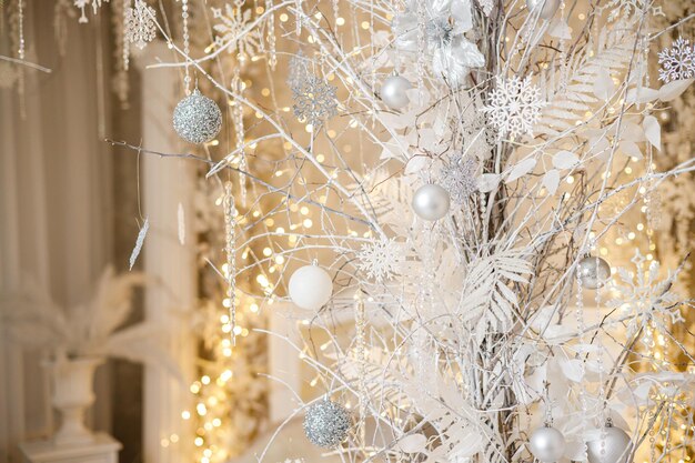 A white Christmas tree is decorated with silver plastic toys Bright festive decoration for the new year