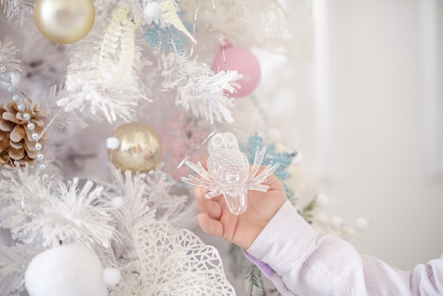 白いクリスマスツリー。新年の木と装飾と男の子の手。