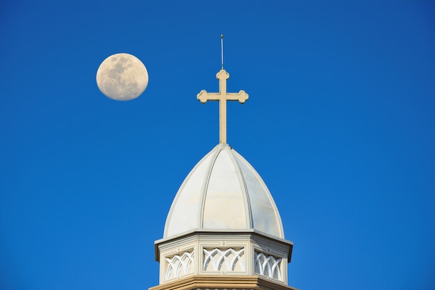 The white church roof has a cross