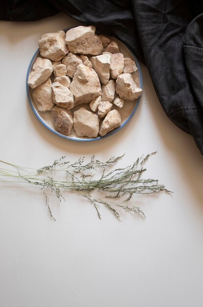 White clay stones with dried leaves on a white background