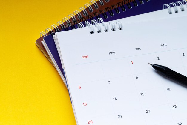 White clean calendar and pen on yellow background with copy space