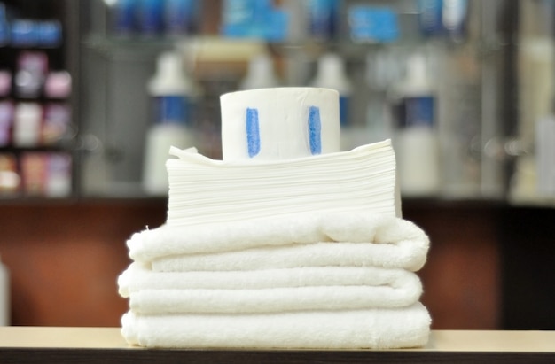 미용사, 일회용 종이 타월, 미용실에서 미용을위한 접착 스트립이있는 보호용 종이 고리를위한 흰색 깨끗한면 수건.