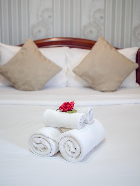 White clean towels decoration with red flower on white clean bed in hotel room