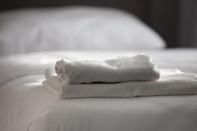 Белые чистые полотенца сложены на кровати отеля