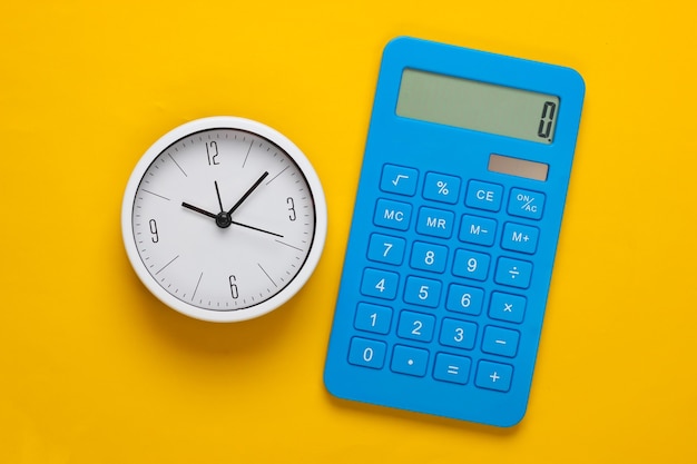 Фото Белые часы и калькулятор на желтом фоне. минималистичный студийный снимок. вид сверху