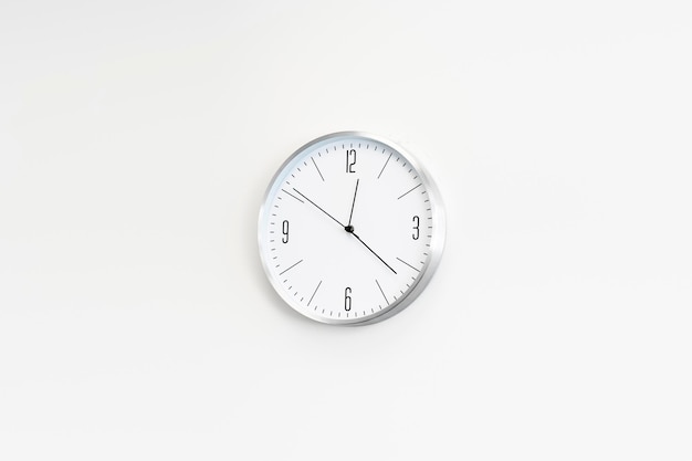 Photo white clock hangs on the white wall place for text copy space