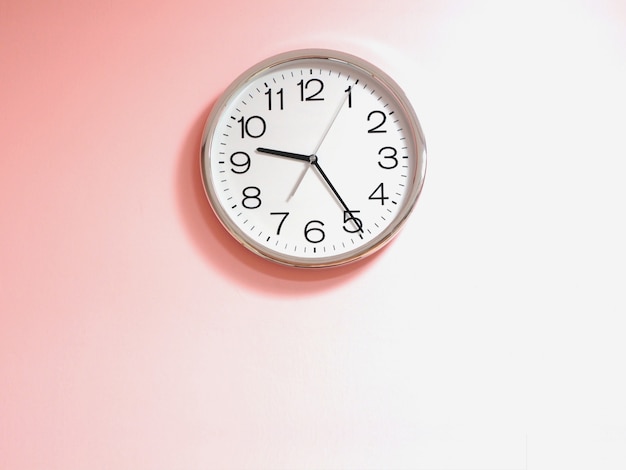 White clock on pink concrete wall