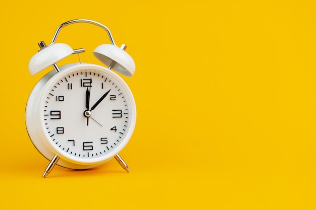 時間の黄色の背景の概念に白い時計は仕事に重要です