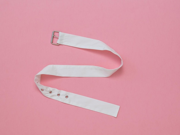 Photo white cloth belt with metal buckle on pink background womens accessory the concept of differentiation