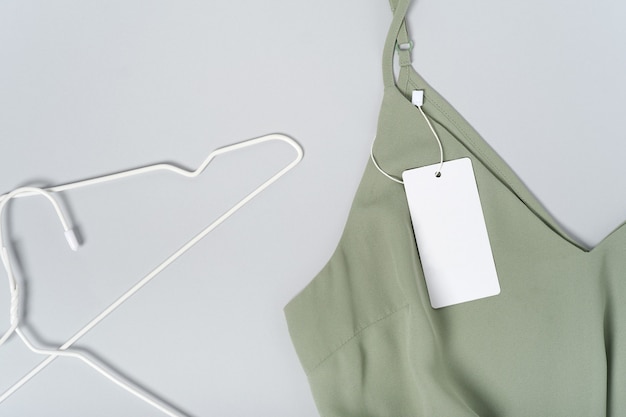 Photo white clothing tag, label blank mockup template. on a premium cotton khaki green blouse, hangers