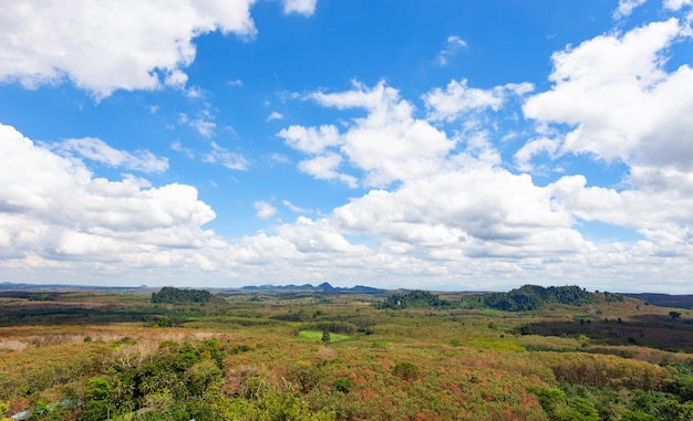 White clouds in blue sky over green mountains covered with rainforests trees.