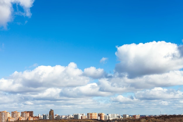 White clouds in blue spring sky over city